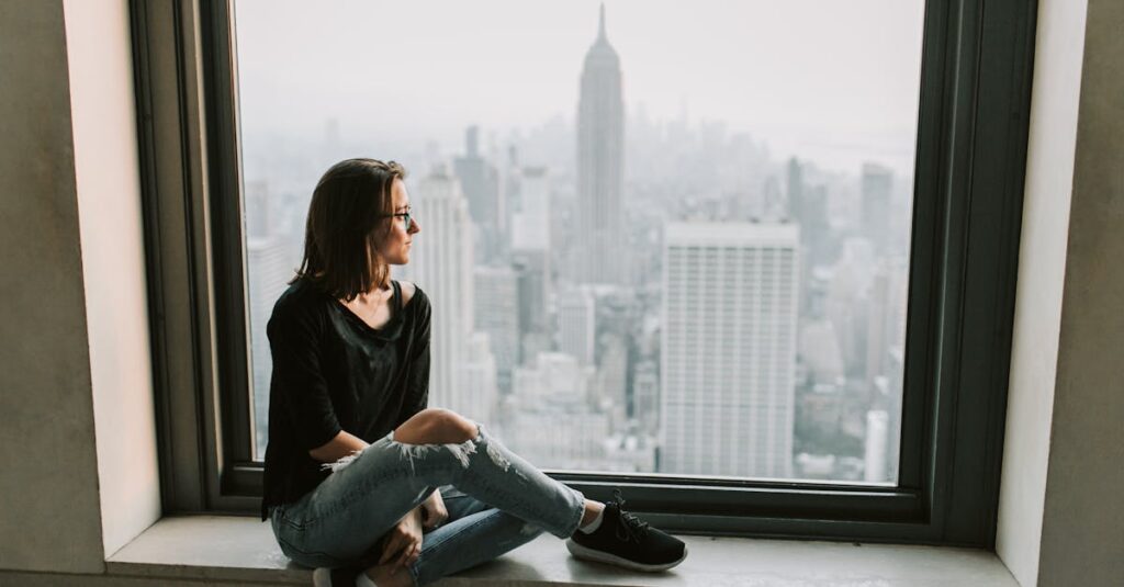 Woman in Black Jacket and Blue Denim Jeans Sitting on Window with the View on Empire State Building