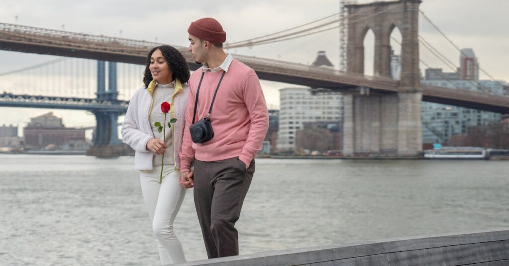 A couple walking by the Brooklyn Bridge, with romance in the air and a red rose in hand.