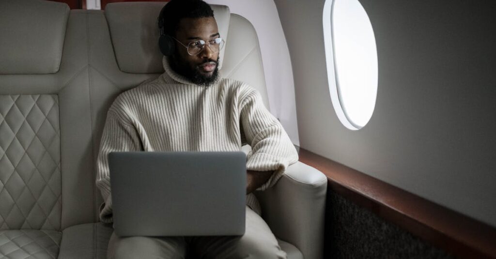 A man wearing headphones uses a laptop in a luxurious airplane cabin.