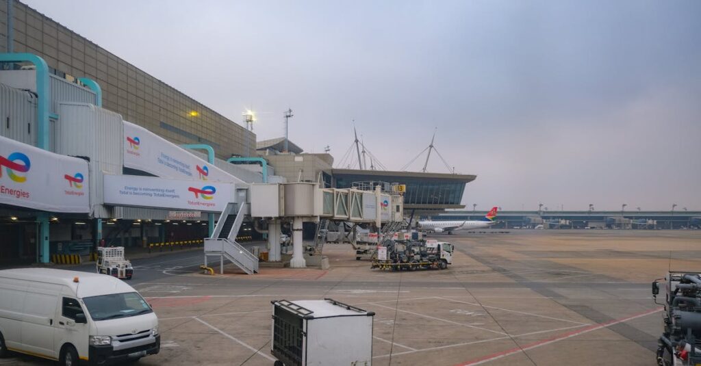 View of an airport apron showcasing vehicles, tarmac, and gates on a cloudy day.