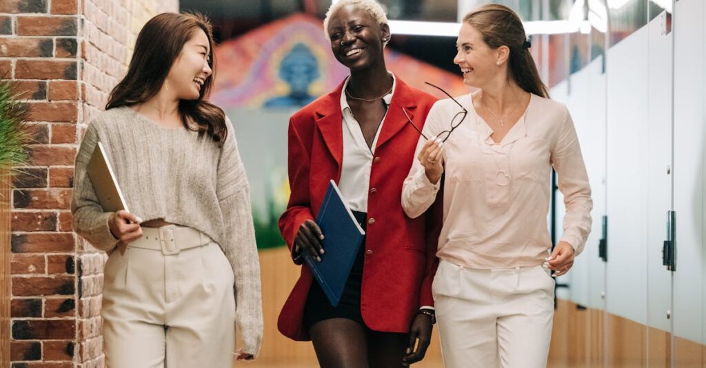 Group of young glad businesswomen in trendy elegant outfits smiling and discussing business strategy in contemporary workspace