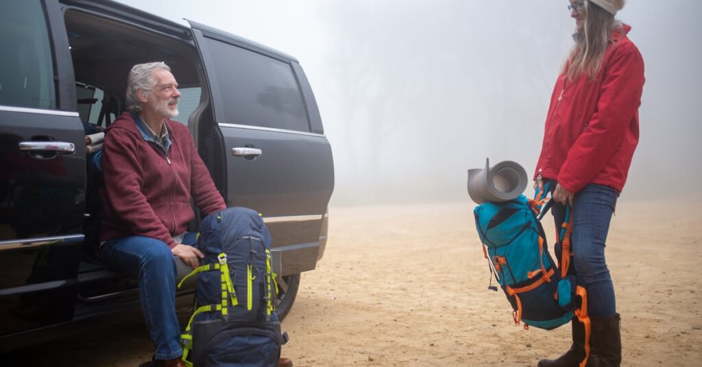 An elderly couple with backpacks preparing for a hike on a foggy day in Portugal.