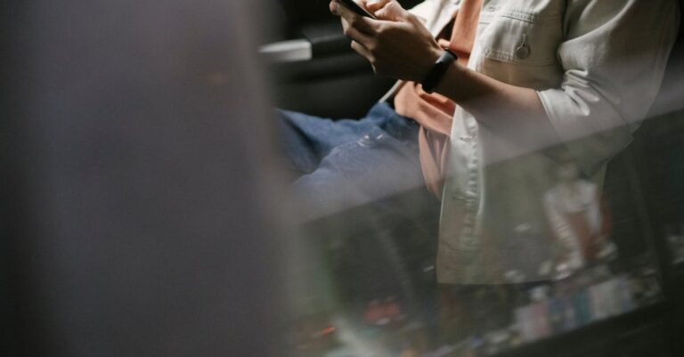 Crop man messaging on smartphone while sitting in car