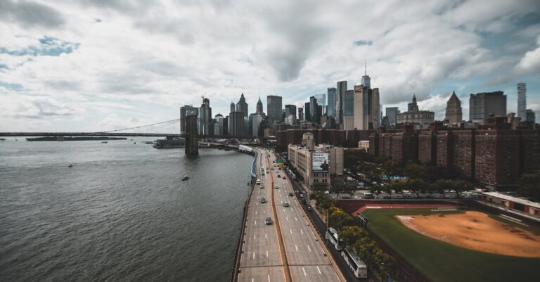 Stunning aerial view of New York City's skyline with river and urban landscape under cloudy skies.