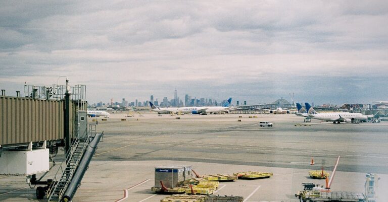 Aircraft waiting on JFK airport apron with New York City skyline in the background.