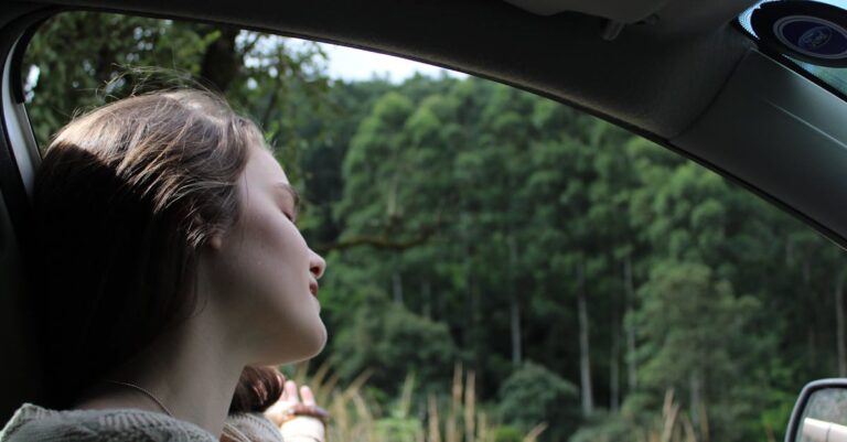 A young woman relaxes while enjoying a serene road trip surrounded by lush greenery.