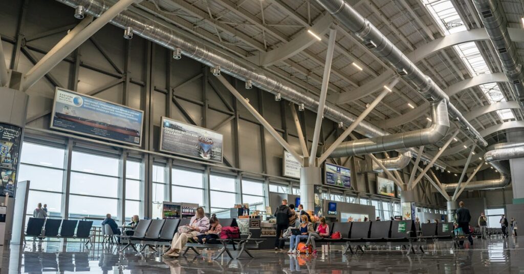 Spacious airport terminal interior with passengers seated and walking, showcasing modern design and large windows.