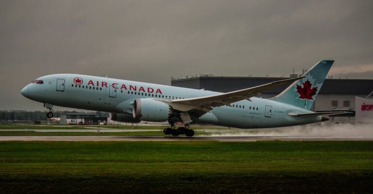 An Air Canada airplane touching down on a runway under cloudy skies, creating a dynamic travel scene.