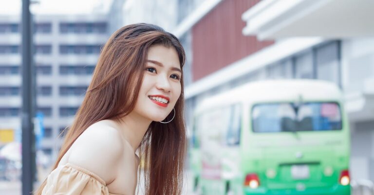 Young woman with long brown hair smiling on Hồ Chí Minh city street, Vietnam.