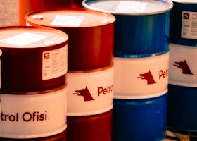 A collection of red and blue oil barrels labeled 'Petrol Ofisi' in an outdoor industrial setting in Turkey.