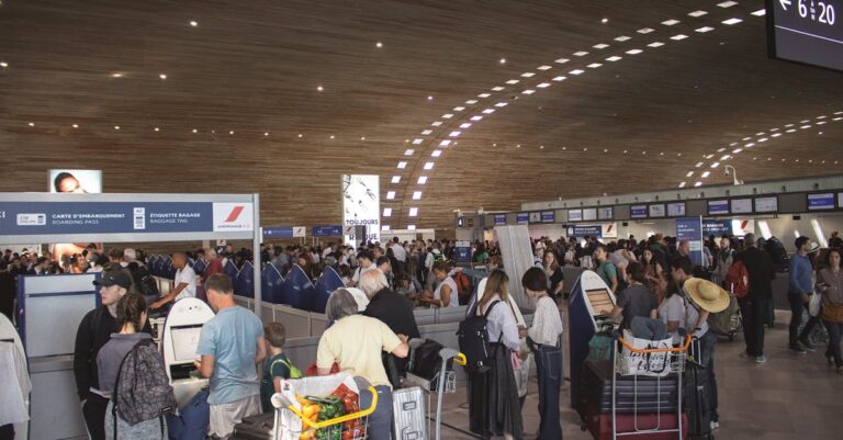 Crowded airport terminal with travellers in line. Indoor setting with modern architecture.