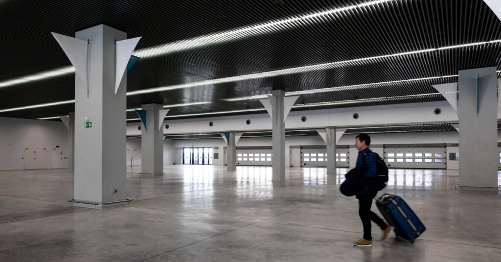 A man with luggage walking through a spacious, modern, empty airport hall.