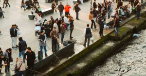 A lively riverside scene with people fishing, socializing, and enjoying the day.