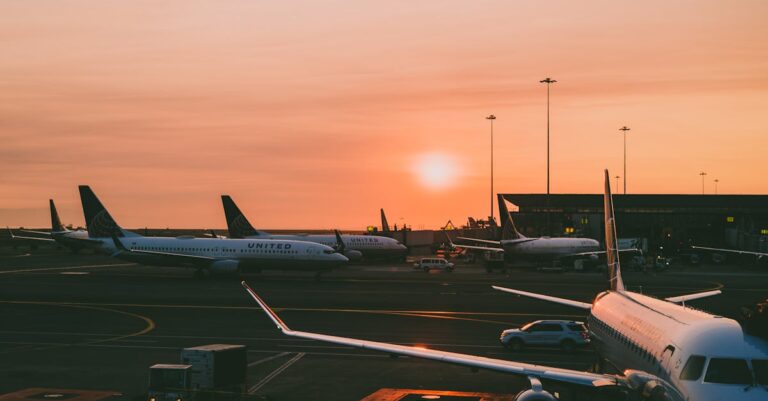 A serene view of parked airplanes at an airport with a beautiful sunset in the background.