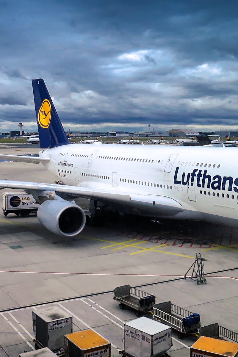 Lufthansa Airbus A380 parked at the airport gate, ready for departure under a dramatic cloudy sky.