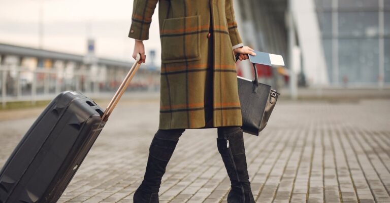 Stylish woman pulls suitcase at airport, ready for travel.