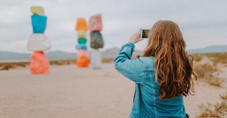 A tourist in denim captures the vibrant Seven Magic Mountains near Las Vegas, Nevada.