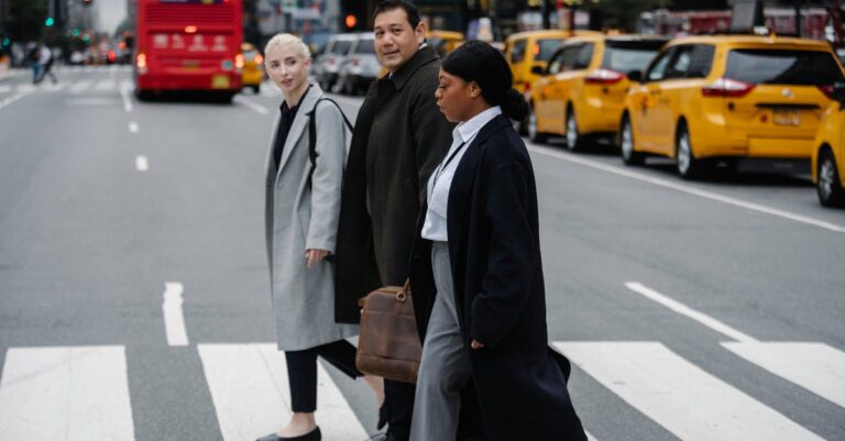 Diverse group of businesspeople crossing a bustling city street, showcasing urban professional life.