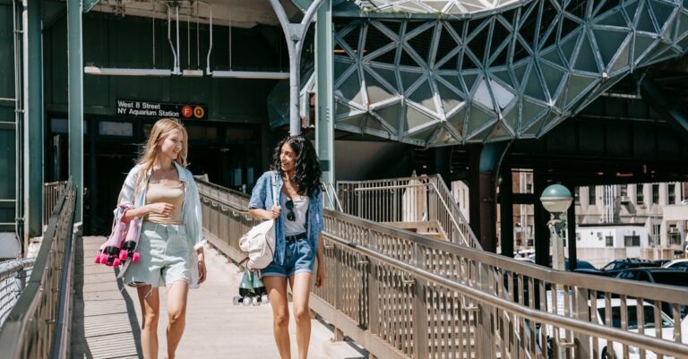 Two women walk and chat at NY Aquarium Station on a sunny summer day.