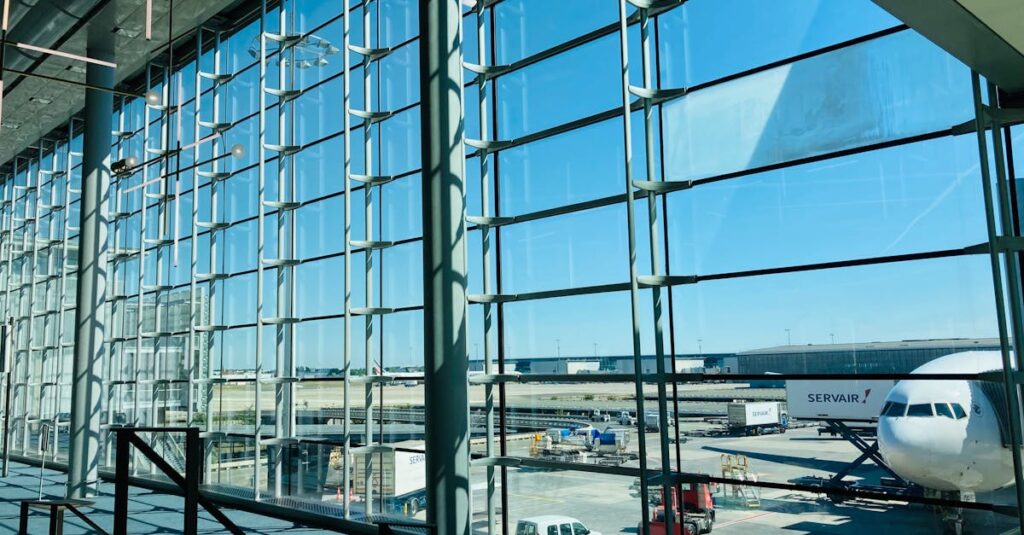 Spacious airport terminal with glass facade overlooking airplane on tarmac.