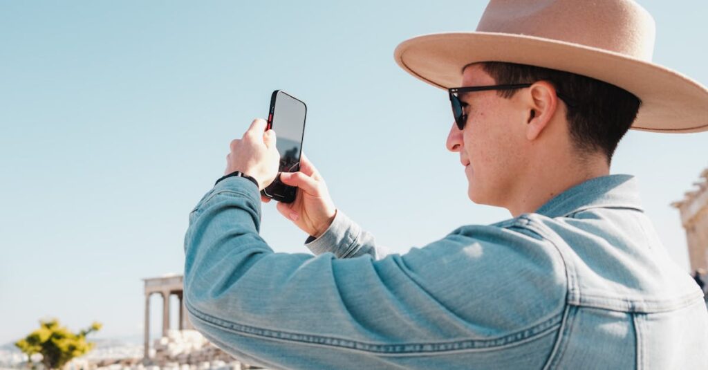 Man in denim jacket taking photo in front of ancient columns, capturing his travel memories.