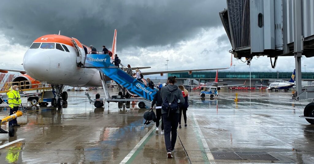 Passengers boarding an aircraft at Edinburgh Airport on a rainy day, highlighting travel dynamics.