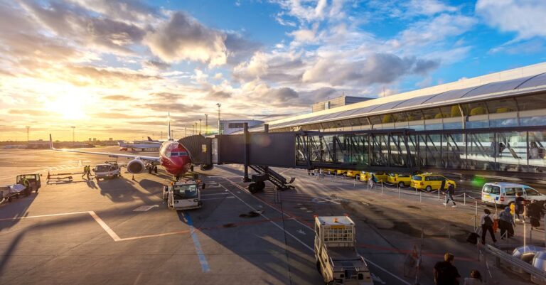 A vibrant sunset at Copenhagen Airport with airplanes and bustling activity.