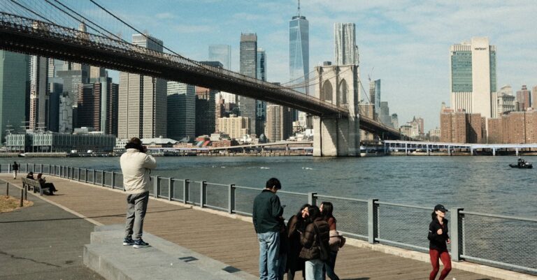 Scenic view of Brooklyn Bridge and New York City skyline with people on promenade.