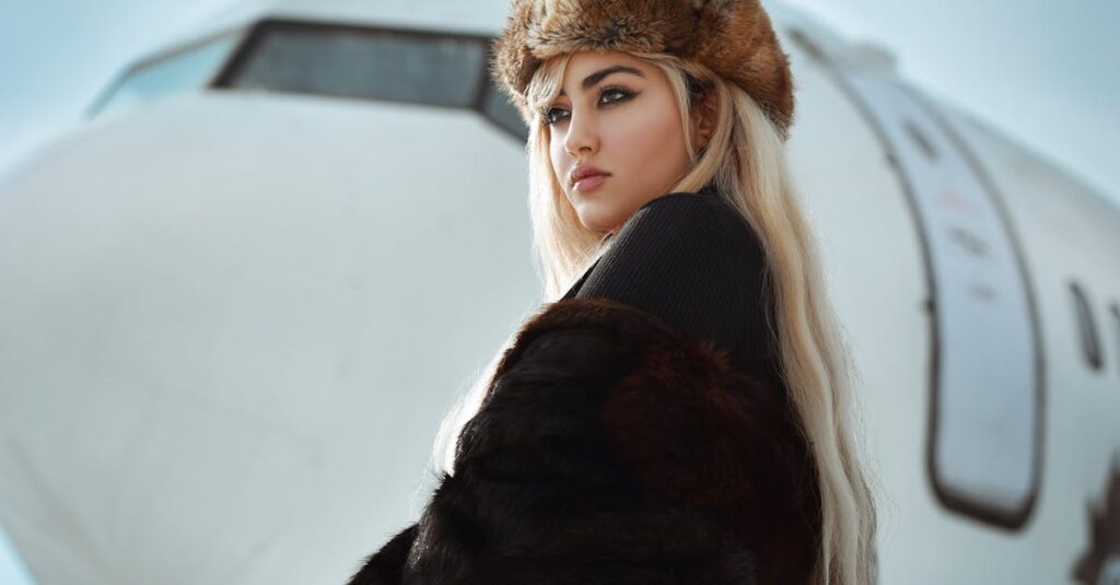 Stylish woman in fur and hat posing near aircraft in winter setting.