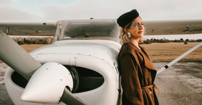 Elegant woman with blond hair standing by small aircraft in daylight