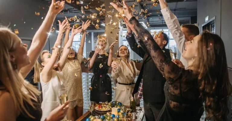 A lively gathering of adults celebrating indoors with confetti and champagne.