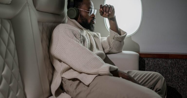 A man relaxing with headphones while traveling on a plane, enjoying leisure in comfort.