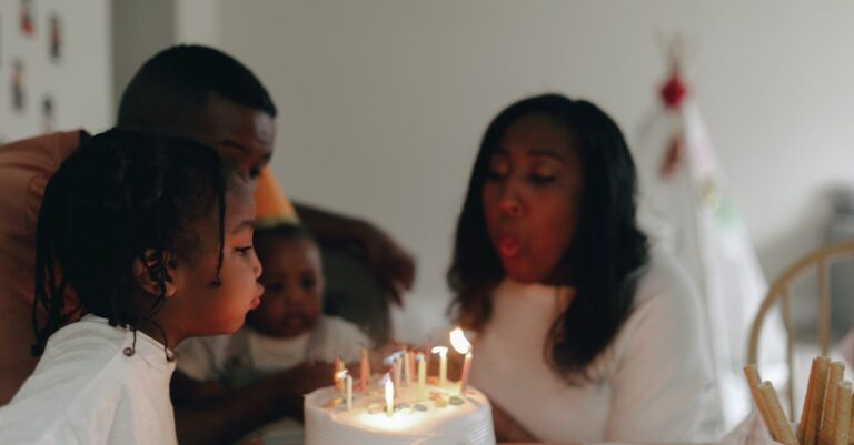 A joyful family celebrating a birthday by blowing out candles on a cake indoors.