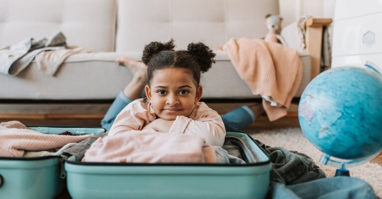 Cute child enjoying playful moments in a suitcase on the floor indoors.