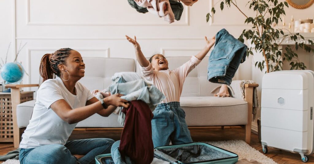 Mother and daughter joyfully packing clothes into a suitcase for a family trip.