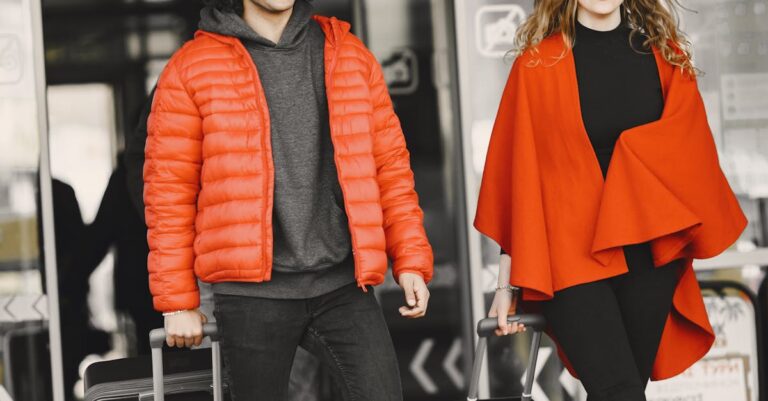 A cheerful couple exiting an airport terminal with luggage, dressed in matching red outfits.