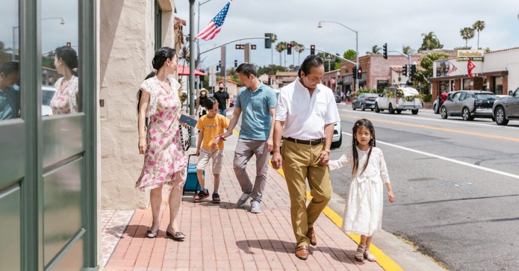 A family walks together on a city sidewalk under a clear sky, enjoying a sunny day.