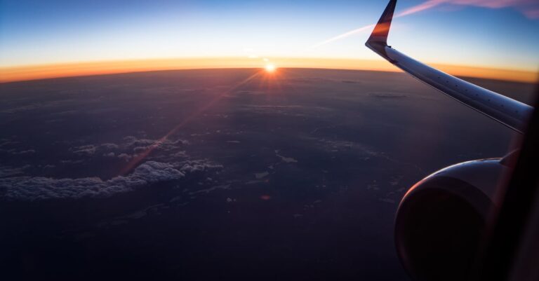 Stunning aerial view from an airplane window showing the wing and a sunset over the clouds.