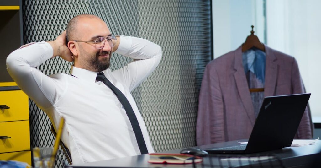 Bald man smiling and relaxing at his desk in a modern office.