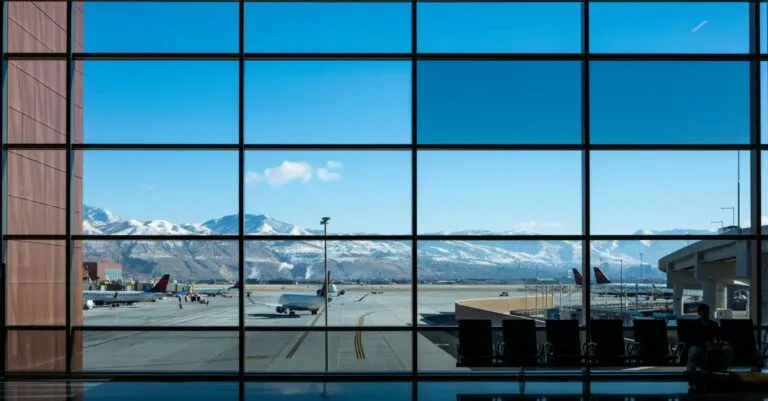 Panoramic view of airport terminal and runway with snow-capped mountains in the background.