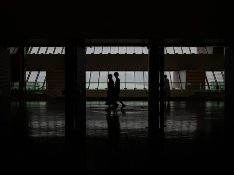 Silhouette of people walking through a modern hallway with large windows in Shanghai, China.