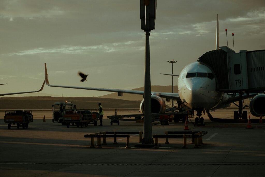Airport Luxury Transportation Service Near by in New York City: Your Honest 2026 Guide to Actually Enjoying the Airport Ride 3 October 9, 2026 A parked airplane at an airport gate with a boarding bridge and vehicles visible at twilight.