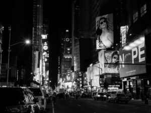 Monochrome View Of Times Square'S Vibrant City Lights And Bustling Street Life At Night.
