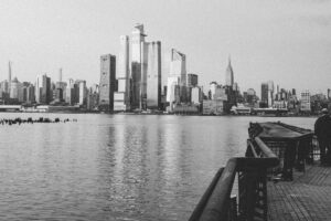 Monochrome View Of Manhattan Skyline From A Waterfront Promenade.