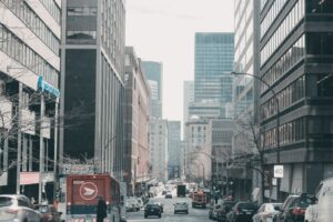 Lively Street Scene In Downtown Montreal, Showcasing Urban Architecture And Bustling Traffic.