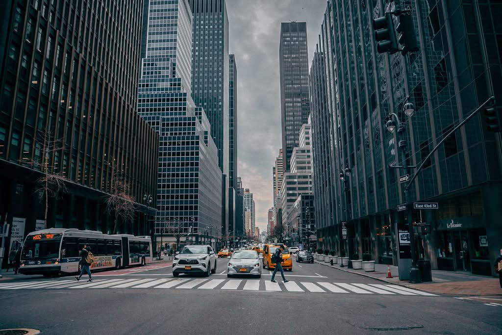 Dynamic view of a busy New York City street with people and skyscrapers, showcasing urban life.