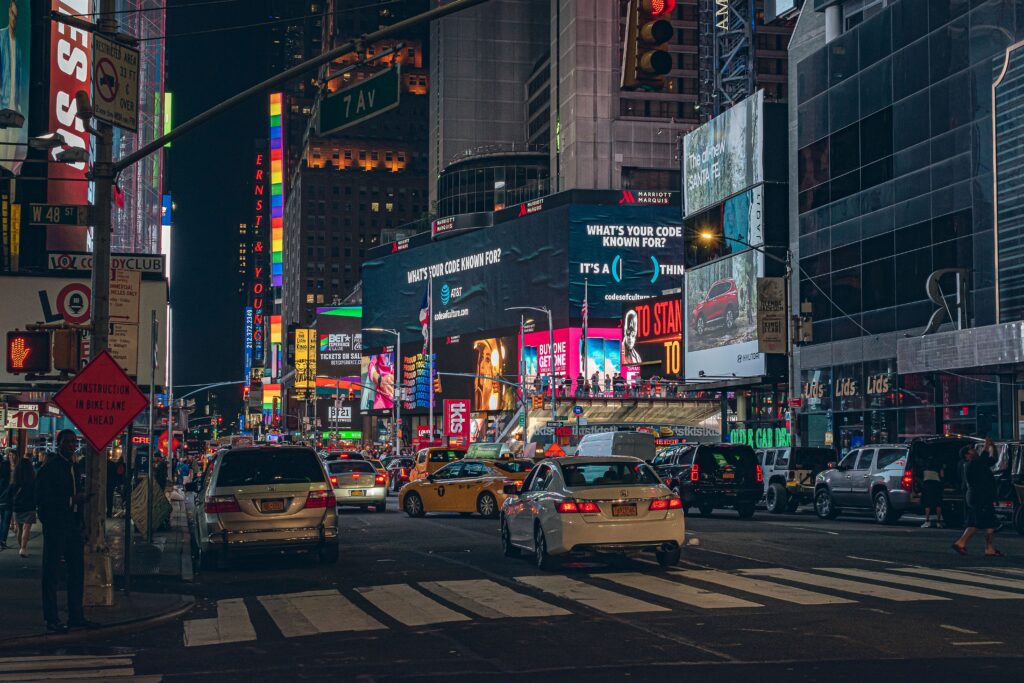 Bustling Times Square At Night With Vibrant Billboards And Traffic Showcasing New York City'S Energy.