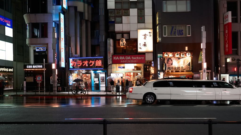 Illuminated street view of Shibuya, Tokyo with bright lights, shops, and pedestrian activity at night.