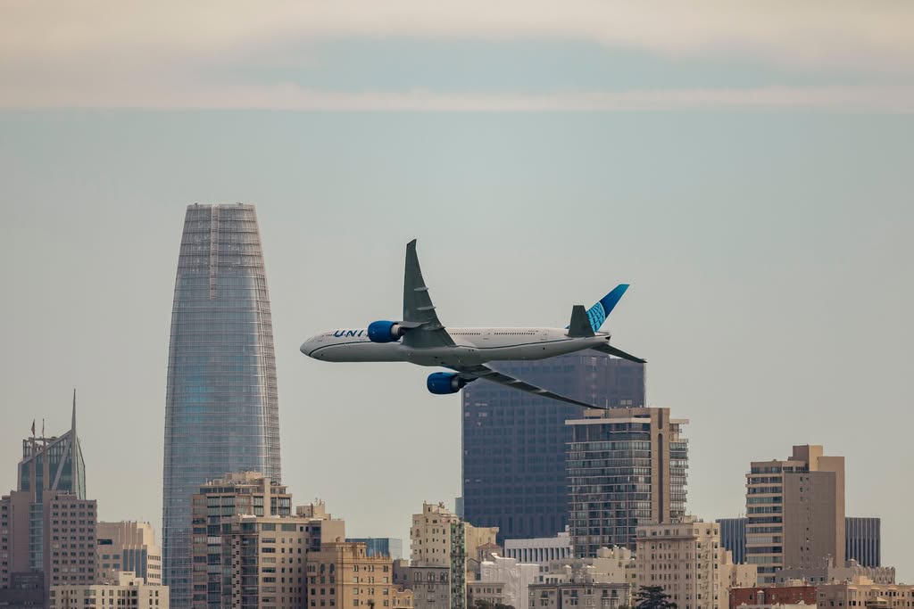 Airplane soaring above the iconic San Francisco skyline, featuring modern skyscrapers.