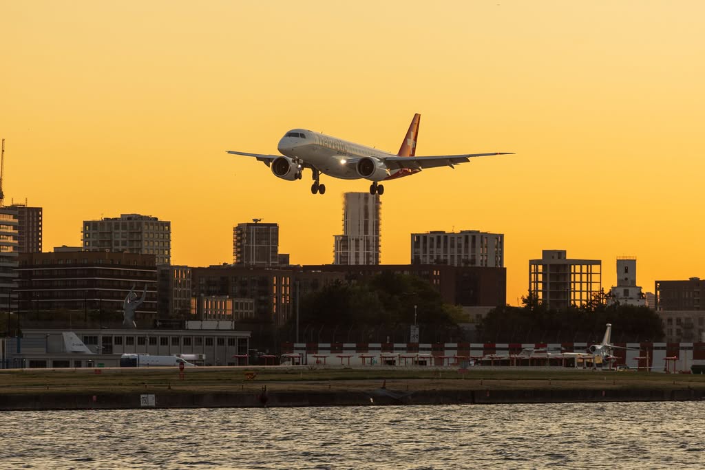 Passenger plane descends over urban skyline at golden sunset